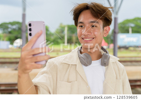 Young non binary tourist traveler in train station using phone Young non binary tourist traveler in train station using phone 128539605