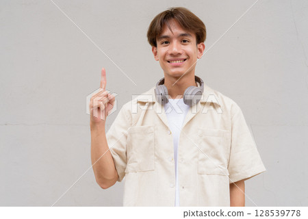 Non binary cute Asian young gay man showing and pointing to copy space Non binary cute Asian young gay man showing and pointing to copy space 128539778