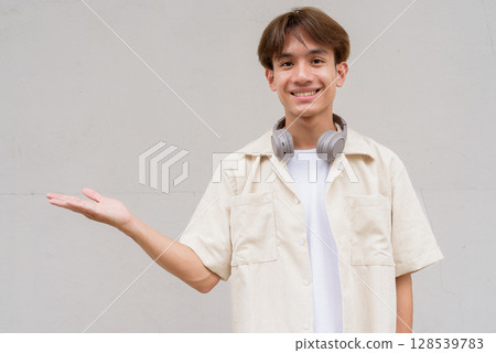 Non binary cute Asian young gay man showing and pointing to copy space Non binary cute Asian young gay man showing and pointing to copy space 128539783