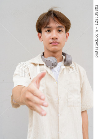 Non binary cute Asian young gay man giving handshake and greeting Non binary cute Asian young gay man giving handshake and greeting 128539802