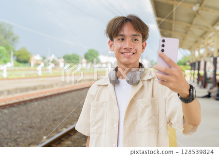 Young non binary tourist traveler in train station using phone 128539824