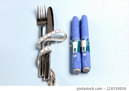 Concept of losing weight with Ozempic. Knife, fork wrapped in a measuring tape and two syringes nearby Concept of losing weight with Ozempic. Knife, fork wrapped in a measuring tape and two syringes nearby 128539839