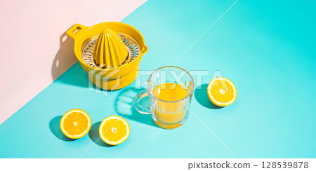 Yellow Lemon Juicer With Fresh Lemons And Glass Of Juice On Trendy Blue Background For Healthy Drink Visuals. Concept Of Vitamin C Boost, Fresh Juices, Summer Refreshment, And Immune Busting Products 128539878