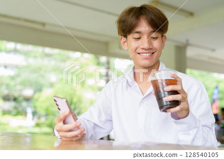 Non binary university student sitting in college campus Non binary university student sitting in college campus 128540105