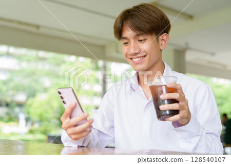 Non binary university student sitting in college campus Non binary university student sitting in college campus 128540107