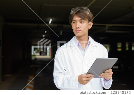 Young scientist student researcher wearing lab coat using tablet computer 128540173