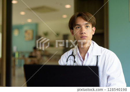 Doctor sitting and using laptop computer Doctor sitting and using laptop computer 128540198
