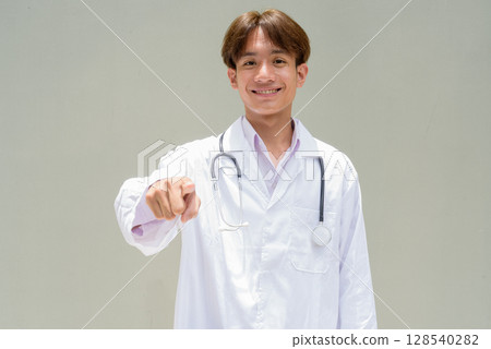 Young healthcare worker wearing lab coat pointing finger Young healthcare worker wearing lab coat pointing finger 128540282