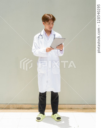 Young healthcare worker wearing lab coat full length portrait 128540295