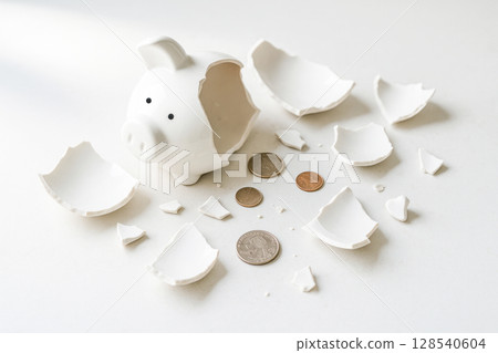 Broken Piggy Bank With Scattered Coins On White Background For Financial Crisis And Savings Concept Visuals. Concept Of Money Loss, Emergency Spending, Budget Failure, And Personal Finance Struggles 128540604
