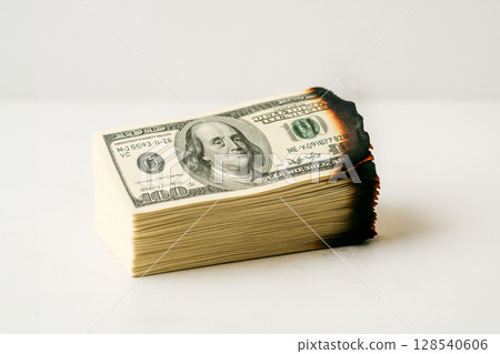 Stack Of Burning Dollar Bills On White Background For Finance Crisis And Inflation Concept Visuals. Concept Of Money Loss, Economic Instability, Risky Investments, And Financial Mismanagement 128540606