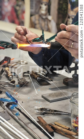 Crafting intricate glass sculptures in a vibrant workshop with skilled hands shaping molten art Crafting intricate glass sculptures in a vibrant workshop with skilled hands shaping molten art 128541388