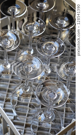 Sparkling glasses await their turn in a stylish bar, ready for drinks to be served at an elegant gathering in the evening light 128541390