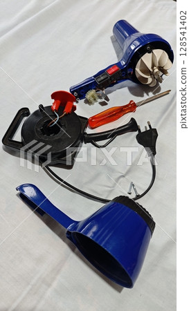Detailed close-up of a blue electric hot air gun and tools for a DIY project on a white surface in a workshop setting 128541402