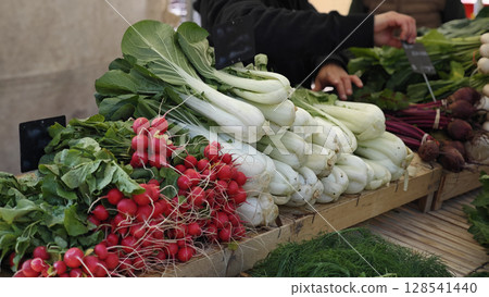 Vibrant farmers market bursting with fresh vegetables showcasing colorful radishes and crisp greens in a lively outdoor setting 128541440
