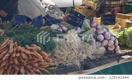 Colorful variety of fresh vegetables displayed at a bustling local market in the heart of the city during a sunny afternoon 128541444