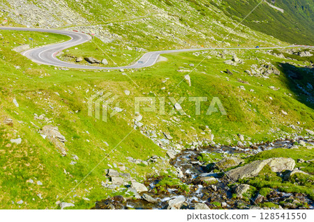 landscape with transfagarasan road in summer. travel romania. scenic view of valley with steep rocky hills and water stream on a sunny morning. alpine scenery of transylvania 128541550