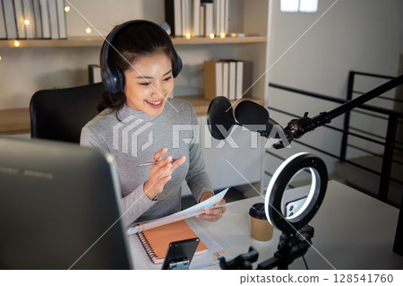 Focused podcast host preparing notes for recording session 128541760
