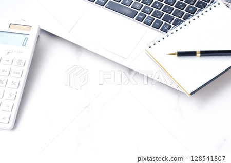 Image of working at a desk with a calculator, pen, notepad, and laptop Image of working at a desk with a calculator, pen, notepad, and laptop 128541807