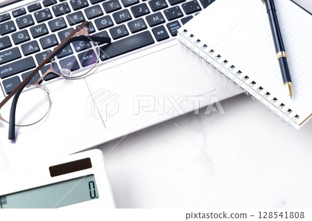 Image of working at a desk with a calculator, pen, notepad, and laptop Image of working at a desk with a calculator, pen, notepad, and laptop 128541808
