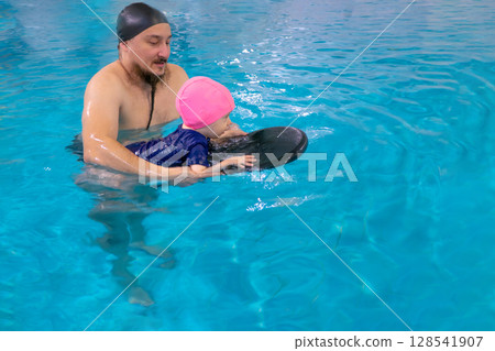 Dad and child are swimming indoor pool. Father teachs to swim. Dad and child are swimming indoor pool. Father teachs to swim. 128541907