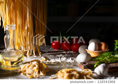 Homemade noodles hanging on wooden dryer rack over messy kitchen table background low angle front view Homemade noodles hanging on wooden dryer rack over messy kitchen table background low angle front view 128541908
