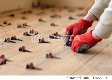 Man Installing Tile Leveling System Components. Man Installing Tile Leveling System Components. 128541910