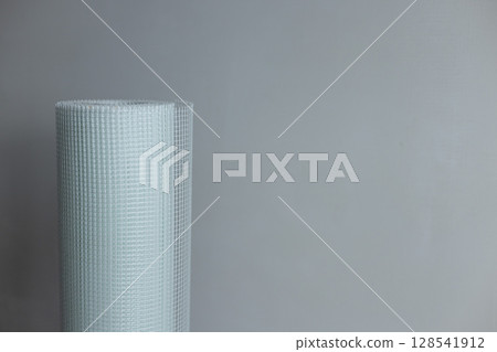 A roll of white plaster mesh for preparatory and painting works on a grey background . A roll of white plaster mesh for preparatory and painting works on a grey background . 128541912