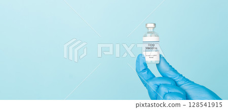 Doctor hand in blue gloves holding BCG vaccine vial over blue background. BCG vaccine used to used to prevent tuberculosis (TB), especially in infants and young children. 128541915