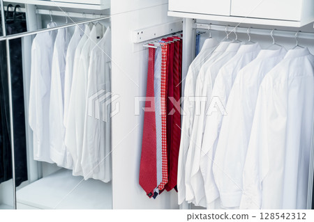 A collection of pristine white shirts, trousers, and ties stood out against a wall of colorful accessories, ranging from bold primary shades to subtle pastels. 128542312