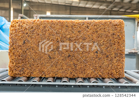 The natural rubber bales products on the industrial automatic conveyor belt machine in a rubber factory. 128542344
