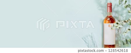 Banner with rose wine. Bottle of natural pink wine with wine glasses on blue background with eucalyptus leaves. Romantic still life with bottle of low alcohol beverage. Mockup, flat lay, copy space Banner with rose wine. Bottle of natural pink wine with wine glasses on blue background with eucalyptus leaves. Romantic still life with bottle of low alcohol beverage. Mockup, flat lay, copy space 128542618