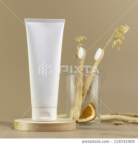 Organic oral care products set. Eco friendly still life with bio toothpaste, toothbrushes in glass jar on wooden podium. Natural teeth hygiene concept. Mockup of tube with toothpaste. Front view 128542908