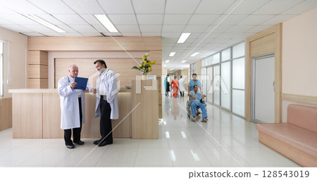 Two doctor in white coat review paperwork at a reception area while patient and nurse move through a bright, contemporary hospital corridor. Two doctor in white coat review paperwork at a reception area while patient and nurse move through a bright, contemporary hospital corridor. 128543019