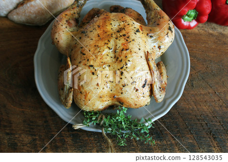 Roasted or baked whole chicken , homemade for a family dinner on a brown  table. Top view with copy space. 128543035