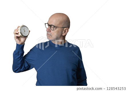 a man looks at an old alarm clock in his hand a man looks at an old alarm clock in his hand 128543253
