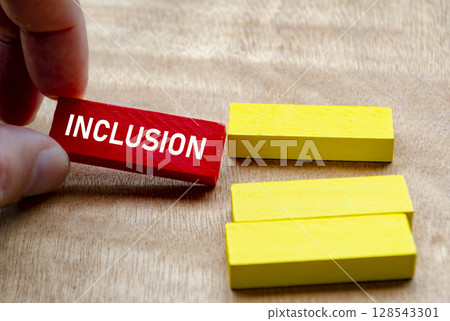 Hand putting Inclusion word on red blocks into the yellow blocks. Diversity and inclusion concept. Hand putting Inclusion word on red blocks into the yellow blocks. Diversity and inclusion concept. 128543301