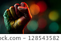 Hand is clenched into a fist, proudly raised up, Pan-African colors, June 19th Juneteenth day, Kwanzaa. Red, black, yellow and green colors. Africa Day. 128543582
