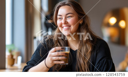 An obese woman at a coffee shop, sipping her drink with a warm, friendly smile 128543759