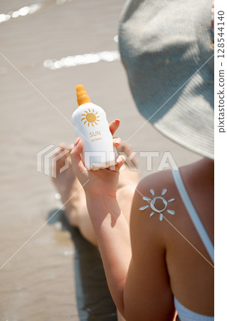 Beautiful Woman apply sun protection cream on her smooth tanned legs. Skin care. Closeup on female Hand smearing moisturizing lotionon. Sunblock concept Beautiful Woman apply sun protection cream on her smooth tanned legs. Skin care. Closeup on female Hand smearing moisturizing lotionon. Sunblock concept 128544140