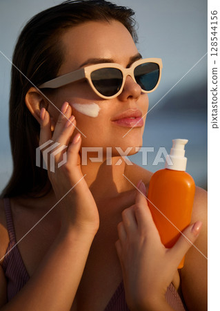 Woman Applying Sunscreen While Outdoors on a Sunny Day Woman Applying Sunscreen While Outdoors on a Sunny Day 128544156