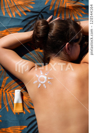 Skin and Body Care.  Woman Applying Sunscreen on Tanned Shoulder in Form of the Sun. Sun Protection. Girl Putting Sun Cream on Skin 128544164