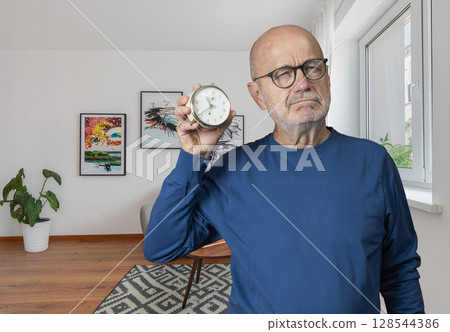 a man with an old alarm clock in his hand 128544386