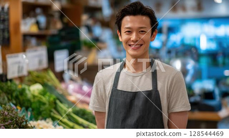 Smiling male clerk at the produce section of a supermarket Smiling male clerk at the produce section of a supermarket 128544469