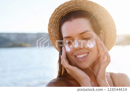 Skincare daily treatment. Beauty close up portrait of young woman with a healthy skin is applying a facial care product. Cream smear. Sun protection. Skincare daily treatment. Beauty close up portrait of young woman with a healthy skin is applying a facial care product. Cream smear. Sun protection. 128544619