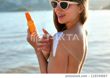 Beauty woman with suntan spf and skincare cosmetics model face portrait, woman applying lotion cream, sunscreen product. Skin and body care. A female smears moisturizing or suntan.Sun protection 128544667