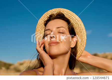Beauty woman with suntan spf and skincare cosmetics model face portrait, woman with moisturising cream, sunscreen product or sun tan lotion on her cheek, luxury facial and skin care. 128544671