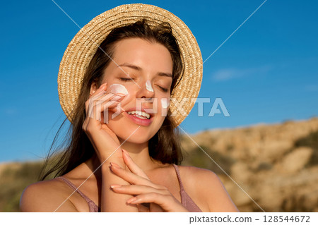 Beauty woman with suntan spf and skincare cosmetics model face portrait, woman with moisturising cream, sunscreen product or sun tan lotion on her cheek, luxury facial and skin care. 128544672