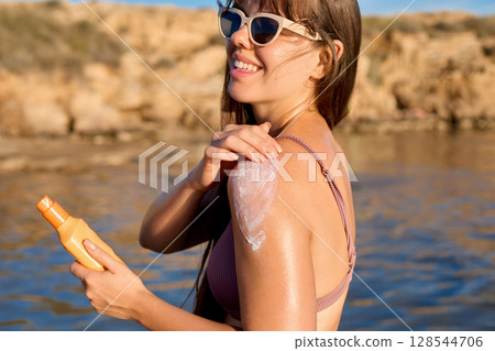 Suntan Lotion. Sexy Young Woman Applying Sunscreen Solar Cream.Sun Protection. Sun Cream. Skin and Body Care.Girl Holding Moisturizing Sunblock. Skin Protection. 128544706