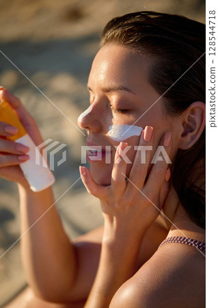 Cream smear. Hydration. Beauty close up portrait of young woman with a healthy glowing skin is applying a skincare product. Girl with suntan spf and cosmetics sunscreen model face portrait Cream smear. Hydration. Beauty close up portrait of young woman with a healthy glowing skin is applying a skincare product. Girl with suntan spf and cosmetics sunscreen model face portrait 128544718